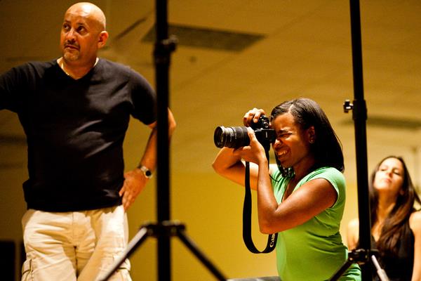 Leading a photography training session demonstrating subject placement and studio lighting.